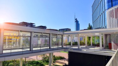 Modern luxury office building.The structure features a glass and concrete walls, showcasing contemporary architecture. The green surroundings of office buildings. Trees and shrubs in the city.