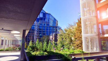 Modern luxury office building.The structure features a glass and concrete walls, showcasing contemporary architecture. The green surroundings of office buildings. Trees and shrubs in the city.