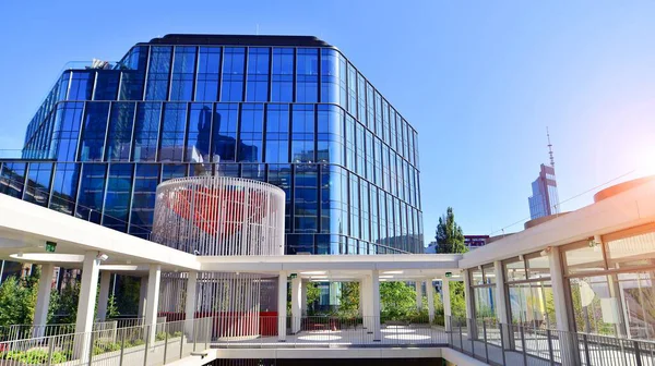 Modern luxury office building.The structure features a glass and concrete walls, showcasing contemporary architecture. The green surroundings of office buildings. Trees and shrubs in the city.