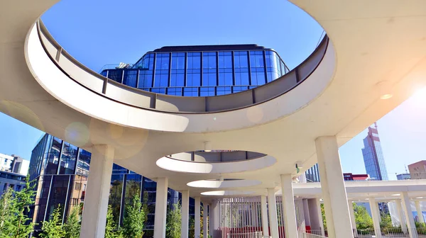 Modern luxury office building.The structure features a glass and concrete walls, showcasing contemporary architecture. The green surroundings of office buildings. Trees and shrubs in the city.