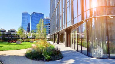 Modern luxury office building.The structure features a glass and concrete walls, showcasing contemporary architecture. The green surroundings of office buildings. Trees and shrubs in the city.