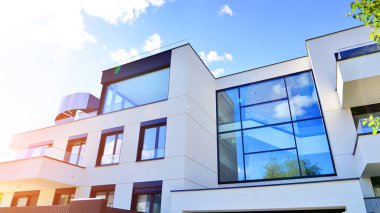 Modern luxury apartment building with balconies.The structure features a glass wall in front, showcasing contemporary architecture.