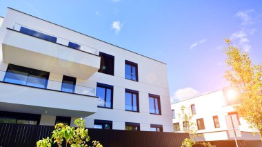 Balkonları ve yeşillikleri olan modern bir apartman. Yapıda cam bir duvar ve önde çağdaş mimari sergilenen yemyeşil bitkiler yer alıyor..