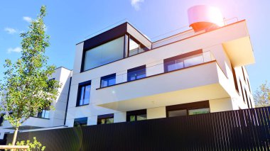 Balkonları ve yeşillikleri olan modern bir apartman. Yapıda cam bir duvar ve önde çağdaş mimari sergilenen yemyeşil bitkiler yer alıyor..