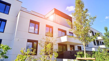 Balkonları ve yeşillikleri olan modern bir apartman. Yapıda cam bir duvar ve önde çağdaş mimari sergilenen yemyeşil bitkiler yer alıyor..