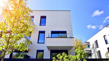 Balkonları ve yeşillikleri olan modern bir apartman. Yapıda cam bir duvar ve önde çağdaş mimari sergilenen yemyeşil bitkiler yer alıyor..