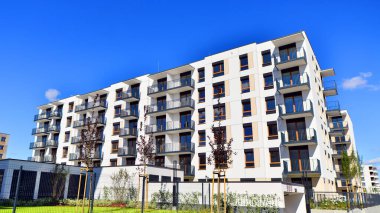 Bereketli yeşil ağaçlarla çevrili ve güneşli bir günde taze bitki örtüsüyle çevrili bir yerleşim yeri. Çağdaş mimari konut kompleksi yeşilliklerle çevrili.