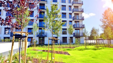 Bereketli yeşil ağaçlarla çevrili ve güneşli bir günde taze bitki örtüsüyle çevrili bir yerleşim yeri. Çağdaş mimari konut kompleksi yeşilliklerle çevrili.