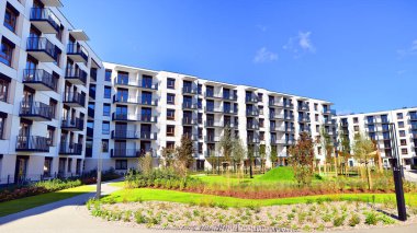 Bereketli yeşil ağaçlarla çevrili ve güneşli bir günde taze bitki örtüsüyle çevrili bir yerleşim yeri. Çağdaş mimari konut kompleksi yeşilliklerle çevrili.