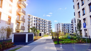 Bereketli yeşil ağaçlarla çevrili ve güneşli bir günde taze bitki örtüsüyle çevrili bir yerleşim yeri. Çağdaş mimari konut kompleksi yeşilliklerle çevrili.