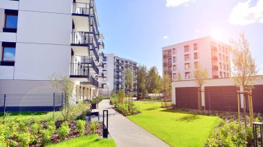 Bereketli yeşil ağaçlarla çevrili ve güneşli bir günde taze bitki örtüsüyle çevrili bir yerleşim yeri. Çağdaş mimari konut kompleksi yeşilliklerle çevrili.