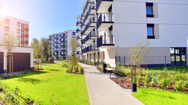 Bereketli yeşil ağaçlarla çevrili ve güneşli bir günde taze bitki örtüsüyle çevrili bir yerleşim yeri. Çağdaş mimari konut kompleksi yeşilliklerle çevrili.