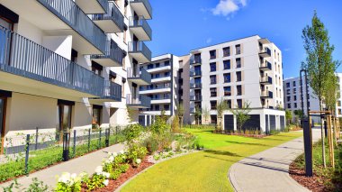 Bereketli yeşil ağaçlarla çevrili ve güneşli bir günde taze bitki örtüsüyle çevrili bir yerleşim yeri. Çağdaş mimari konut kompleksi yeşilliklerle çevrili.