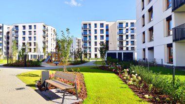 Bereketli yeşil ağaçlarla çevrili ve güneşli bir günde taze bitki örtüsüyle çevrili bir yerleşim yeri. Çağdaş mimari konut kompleksi yeşilliklerle çevrili.