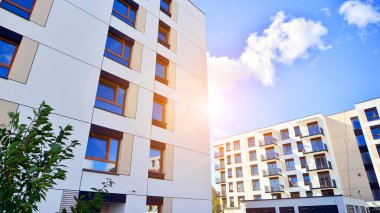 Bereketli yeşil ağaçlarla çevrili ve güneşli bir günde taze bitki örtüsüyle çevrili bir yerleşim yeri. Çağdaş mimari konut kompleksi yeşilliklerle çevrili.