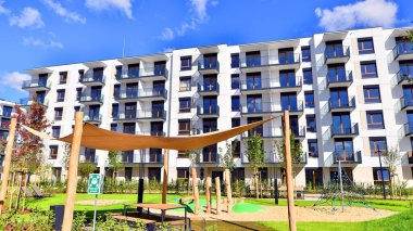 Bereketli yeşil ağaçlarla çevrili ve güneşli bir günde taze bitki örtüsüyle çevrili bir yerleşim yeri. Çağdaş mimari konut kompleksi yeşilliklerle çevrili.