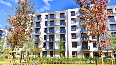 Bereketli yeşil ağaçlarla çevrili ve güneşli bir günde taze bitki örtüsüyle çevrili bir yerleşim yeri. Çağdaş mimari konut kompleksi yeşilliklerle çevrili.