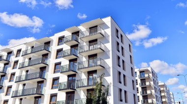 Bereketli yeşil ağaçlarla çevrili ve güneşli bir günde taze bitki örtüsüyle çevrili bir yerleşim yeri. Çağdaş mimari konut kompleksi yeşilliklerle çevrili.