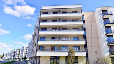 Bereketli yeşil ağaçlarla çevrili ve güneşli bir günde taze bitki örtüsüyle çevrili bir yerleşim yeri. Çağdaş mimari konut kompleksi yeşilliklerle çevrili.