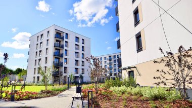 Bereketli yeşil ağaçlarla çevrili ve güneşli bir günde taze bitki örtüsüyle çevrili bir yerleşim yeri. Çağdaş mimari konut kompleksi yeşilliklerle çevrili.