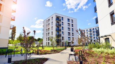 Bereketli yeşil ağaçlarla çevrili ve güneşli bir günde taze bitki örtüsüyle çevrili bir yerleşim yeri. Çağdaş mimari konut kompleksi yeşilliklerle çevrili.