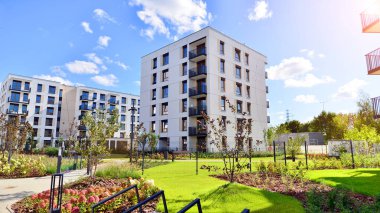 Bereketli yeşil ağaçlarla çevrili ve güneşli bir günde taze bitki örtüsüyle çevrili bir yerleşim yeri. Çağdaş mimari konut kompleksi yeşilliklerle çevrili.