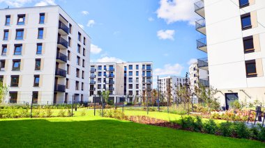 Bereketli yeşil ağaçlarla çevrili ve güneşli bir günde taze bitki örtüsüyle çevrili bir yerleşim yeri. Çağdaş mimari konut kompleksi yeşilliklerle çevrili.