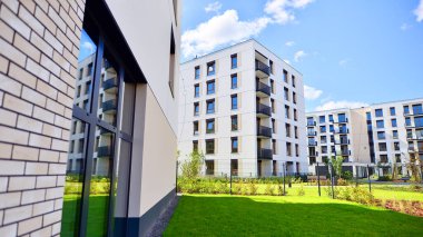 Bereketli yeşil ağaçlarla çevrili ve güneşli bir günde taze bitki örtüsüyle çevrili bir yerleşim yeri. Çağdaş mimari konut kompleksi yeşilliklerle çevrili.