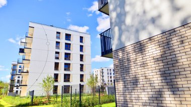 Bereketli yeşil ağaçlarla çevrili ve güneşli bir günde taze bitki örtüsüyle çevrili bir yerleşim yeri. Çağdaş mimari konut kompleksi yeşilliklerle çevrili.