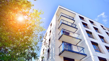 Bereketli yeşil ağaçlarla çevrili ve güneşli bir günde taze bitki örtüsüyle çevrili bir yerleşim yeri. Çağdaş mimari konut kompleksi yeşilliklerle çevrili.