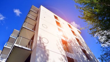 Bereketli yeşil ağaçlarla çevrili ve güneşli bir günde taze bitki örtüsüyle çevrili bir yerleşim yeri. Çağdaş mimari konut kompleksi yeşilliklerle çevrili.