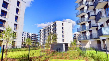 Bereketli yeşil ağaçlarla çevrili ve güneşli bir günde taze bitki örtüsüyle çevrili bir yerleşim yeri. Çağdaş mimari konut kompleksi yeşilliklerle çevrili.
