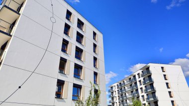 Bereketli yeşil ağaçlarla çevrili ve güneşli bir günde taze bitki örtüsüyle çevrili bir yerleşim yeri. Çağdaş mimari konut kompleksi yeşilliklerle çevrili.