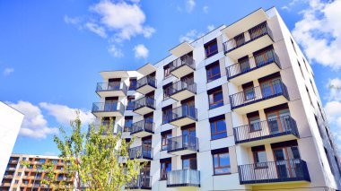 Bereketli yeşil ağaçlarla çevrili ve güneşli bir günde taze bitki örtüsüyle çevrili bir yerleşim yeri. Çağdaş mimari konut kompleksi yeşilliklerle çevrili.