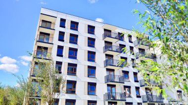 Bereketli yeşil ağaçlarla çevrili ve güneşli bir günde taze bitki örtüsüyle çevrili bir yerleşim yeri. Çağdaş mimari konut kompleksi yeşilliklerle çevrili.