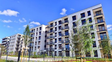 Bereketli yeşil ağaçlarla çevrili ve güneşli bir günde taze bitki örtüsüyle çevrili bir yerleşim yeri. Çağdaş mimari konut kompleksi yeşilliklerle çevrili.