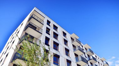 Bereketli yeşil ağaçlarla çevrili ve güneşli bir günde taze bitki örtüsüyle çevrili bir yerleşim yeri. Çağdaş mimari konut kompleksi yeşilliklerle çevrili.