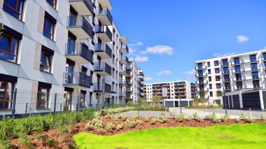Bereketli yeşil ağaçlarla çevrili ve güneşli bir günde taze bitki örtüsüyle çevrili bir yerleşim yeri. Çağdaş mimari konut kompleksi yeşilliklerle çevrili.