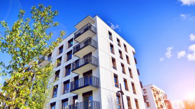 Bereketli yeşil ağaçlarla çevrili ve güneşli bir günde taze bitki örtüsüyle çevrili bir yerleşim yeri. Çağdaş mimari konut kompleksi yeşilliklerle çevrili.