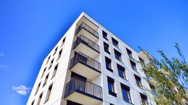 Bereketli yeşil ağaçlarla çevrili ve güneşli bir günde taze bitki örtüsüyle çevrili bir yerleşim yeri. Çağdaş mimari konut kompleksi yeşilliklerle çevrili.