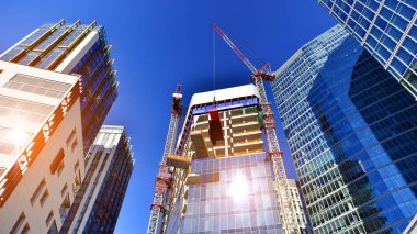 Crane inşaat alanında, yüksek binalarla çevrili bir yerde. Yüksek apartman ve ofis binaları civarında inşaat halindeki ofis binası.