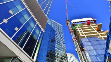 Crane inşaat alanında, yüksek binalarla çevrili bir yerde. Yüksek apartman ve ofis binaları civarında inşaat halindeki ofis binası.