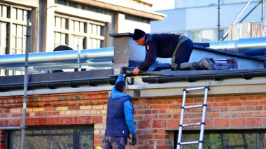 Varşova, Polonya. 6 Kasım 2025. İki işçi çatıyı tamir ediyor.