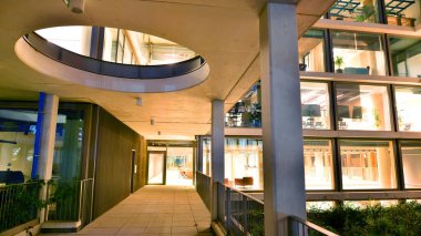 Şehir merkezindeki modern ofis binası gece aydınlandı. Aydınlatılmış pencereler modern bir cephenin mimari şebekesine karşı. Gece versiyonunda beton ve cam cephe.