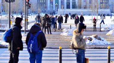 Varşova, Polonya. 5 Ocak 2026. Yayalar kışın yaya geçidinde karşıdan karşıya geçerler. Arka planda, şehir, binalar, arabalar..