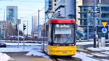 Varşova, Polonya. 5 Ocak 2026. Toplu taşıma durağıyla modern sarı tramvay Avrupa şehir merkezi.