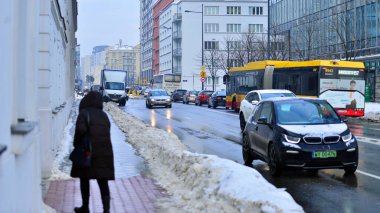 Varşova, Polonya. 15 Ocak 2026. Kış günü şehir merkezinde yol trafiği. Bir kış günü şehir merkezinde trafik ve binaların olduğu bir cadde manzarası.