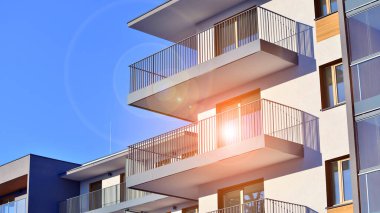 Şık yüzlü ve geniş pencereli modern konut binası. Büyüyen bir mahallede çağdaş şehir mimarisi. Güneşli bir gökyüzünün altında gayrimenkul gelişimi.