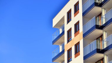 Şık yüzlü ve geniş pencereli modern konut binası. Büyüyen bir mahallede çağdaş şehir mimarisi. Güneşli bir gökyüzünün altında gayrimenkul gelişimi.