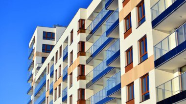 Şık yüzlü ve geniş pencereli modern konut binası. Büyüyen bir mahallede çağdaş şehir mimarisi. Güneşli bir gökyüzünün altında gayrimenkul gelişimi.